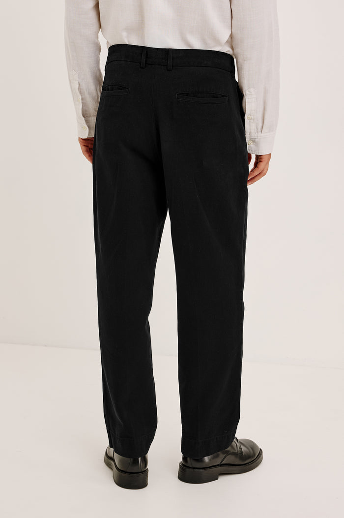 Ezra Pant in Brushed Cotton Twill With Relaxed Fit, Single Front Pleats, Ankle-Length Hem, Zip Fly, Side Pockets, and Back Double-Welt Pockets in Black Colorway - Lower Body Back View Featured on Model