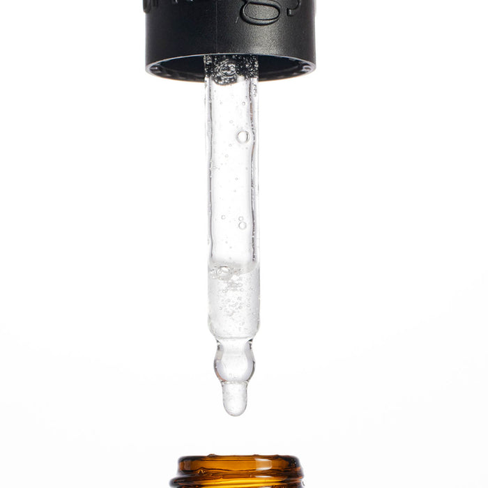 Close-up of a dropper with liquid being dispensed on a white background
