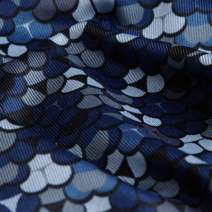Close-up of Whale Tail - Navy - Polo fabric with a repeating pattern of overlapping, rounded blue, black, and gray scales. Slight wrinkles add texture, and moisture-wicking properties keep you dry and comfortable.
