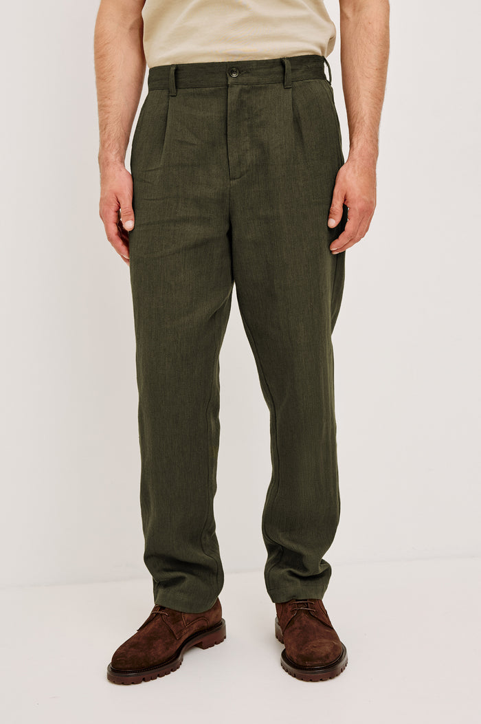 Zimmer Pant in Cotton Linen Wool Blend With Relaxed Fit, Tapered Leg, Side Pockets, Zip Fly, Belt Loops, and Back Welt Pockets in Deep Olive Colorway - Lower Body Front View Featured on Model