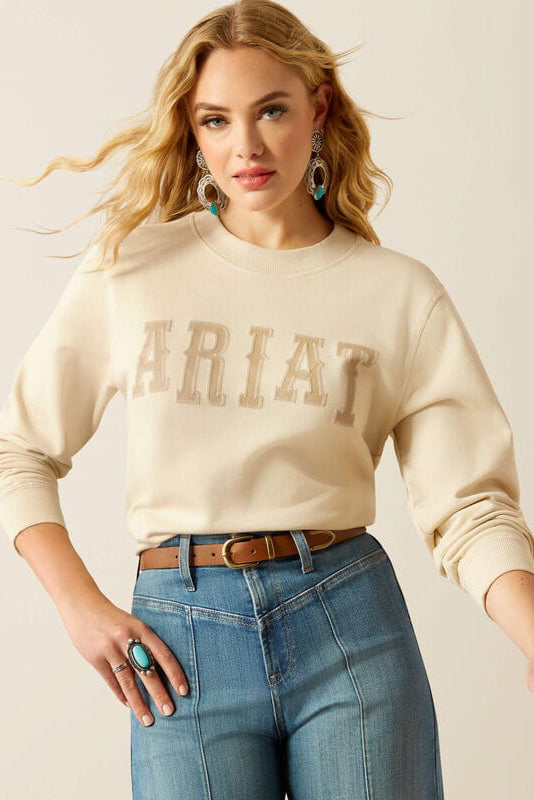 Woman wearing Ariat sweatshirt and jeans.