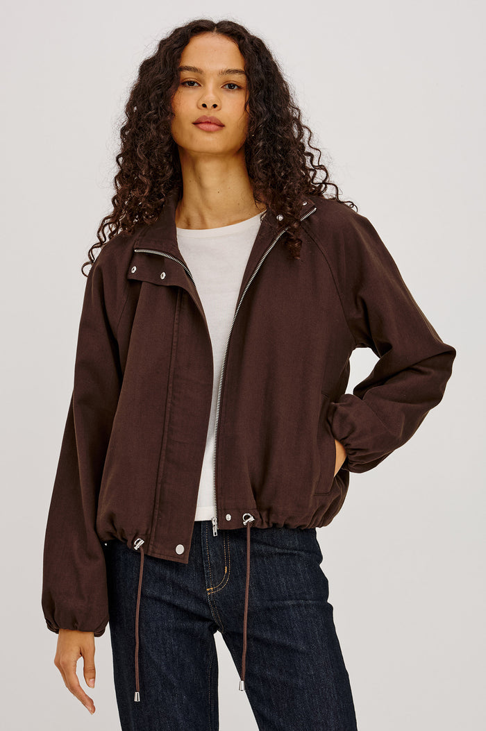 Blake Jacket in TENCEL™ Denim With Relaxed Fit, High Funnel Neck, Double Button Closures, Drop Shoulder Sleeves With Elastic Cuffs, and Cropped Drawstring Hem in Espresso Colorway - Full Body Front View Featured on Model