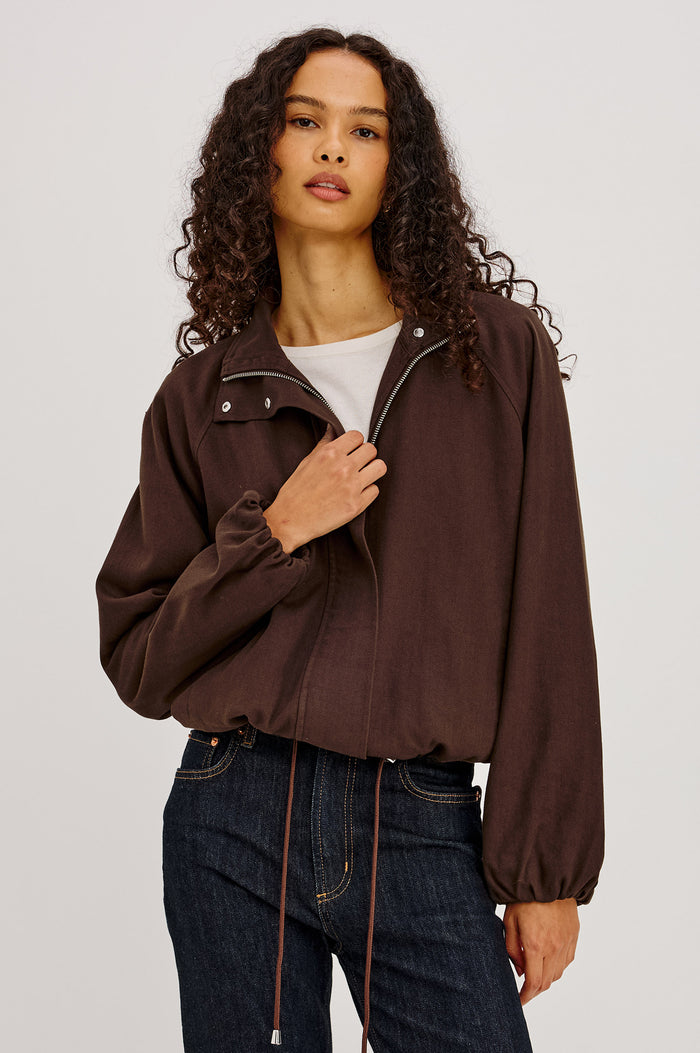 Blake Jacket in TENCEL™ Denim With Relaxed Fit, High Funnel Neck, Double Button Closures, Drop Shoulder Sleeves With Elastic Cuffs, and Cropped Drawstring Hem in Espresso Colorway - Upper Body Front View Featured on Model