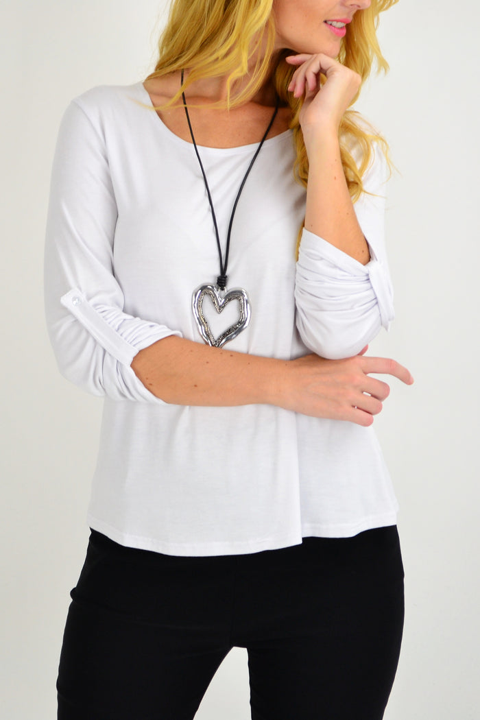 White Lilia button-up long sleeve basic top hanging on a rack, showcasing a classic collar and fitted design.